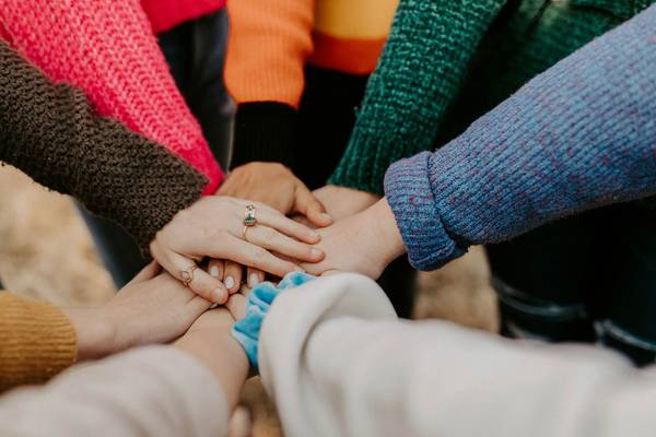 Quelle: unsplash.com / Hannah Busing, https://unsplash.com/de/fotos/person-im-roten-pullover-die-babys-hand-halt-Zyx1bK9mqmA Teambuilding: Hände werden in Mitte zusammen gehalten
